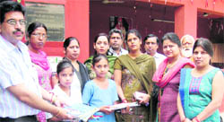  Needy children with their set of textbooks stand along with the members of the Women Welfare Council in Ludhiana on Tuesday.