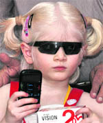 A child poses with a mobile phone, which has been specially manufactured for the visually impaired, in New Delhi on Monday. Priced at Rs 2,600, the phone has been jointly designed by INTEX and the National Association for the Blind