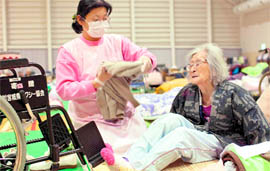 Sueko Suzuki (87) recieves help from a caretaker at an evacuation centre for those displaced by the earthquake and tsunami in Ishinomaki on Tuesday.