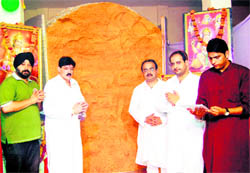 Members of the Sri Balaji Sankat Baghian stand beside a ladoo weighing 15,000 kg, which was specially made to mark Hanuman Jayanti, in Amritsar