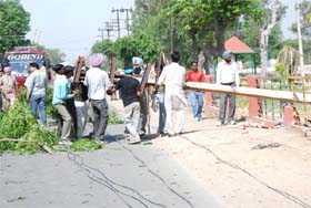Workers of the Punjab State Power Corporation Limited clearing off an electricity pole, which was uprooted after squall that hit the region on Thursday, from a road in Bathinda on Friday