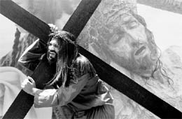 A Christian devotee, portraying Jesus Christ, carries a cross during a Good Friday procession in Mumbai