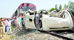 Railway workers try to remove the mangled remains of the Scorpio that was hit by a train