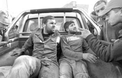A rebel fighter points at captured Gaddafi soldiers in the back of a rebel forces pick-up truck outside a Misrata hospital