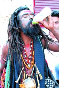 A sadhu smeared with ash quenches his thirst on a hot sunny day in Bathinda on Sunday