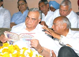 Lok Sabha former Speaker Bal Ram Jakhar reads the souvenir while writer JC Nagpal explains a few points at a free medical camp in Abohar