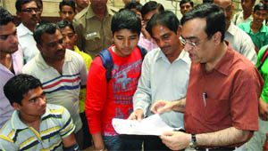 The minister of state for youth affairs and sports Ajay Maken sees the registration form for Come and Play Scheme at MDC National Stadium in New Delhi on Monday.