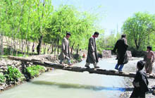 People cross a makeshift bridge over a seasonal river at Chowgam village of the Devsar block to cast their vote in the fourth phase of the panchayat elections on Monday. 