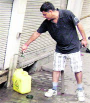A social activist closes the nozzle of a tap that had been flowing continuously in the Main Bazar area in Mandi Ahmedgarh.