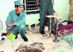 THE GREAT ESCAPE: An Afghan cop sits next to the entrance of the tunnel