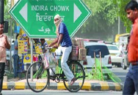 A man covers his face to save himself from the duststorm and heat as he cycles at Connaught Place in New Delhi