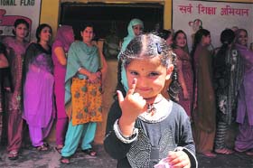 A young girl shows her index finger outside a polling booth in Jammu where an official obliged her by putting ink on her finger