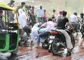 A two-wheeler rider loses his balance as his pillion rider, holding an LPG cylinder, tries to retain balance on Ludhianas Gill road spilled with molasses on Tuesday.