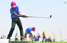 Village children try their hand at golf at Mullanpur.
