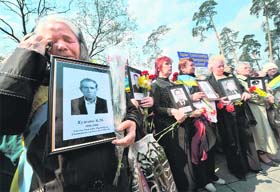 A woman who became a widow during the Chernobyl disaster cries as she holds a portrait of her late husband during a memorial service at the Chernobyl Victims' Monument in Kiev on Tuesday