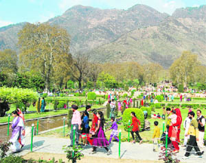 Tourists enjoy at the Nishat Mughal Gardens overlooking the Dal Lake in Srinagar on Wednesday. 