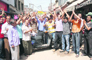 Shopkeepers of the Purani Mandi Market stage a protest against the ERA Department for not repairing damaged roads in Jammu on Wednesday.