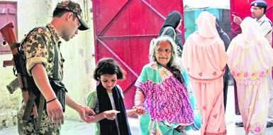 A Central force jawan checks voter identity cards at a polling station during the third phase of Assembly elections in Kolkata on Wednesday.