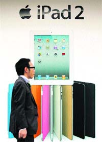 A man passes by a poster of Apple Inc's iPad 2 in Tokyo on Thursday. Apple launched its new generation of iPad in Japan on Thursday