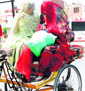 Two women cover their faces with dupattas to protect themselves from sun rays in Amritsar