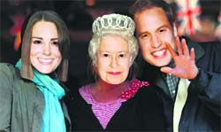 People wear masks of Queen Elizabeth (centre), Kate Middleton (left) and Prince William, at a cafe in London