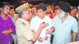 Applicants argue with a police official during the auction of Super Bazaar booths in Chandigarh