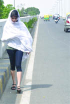 A girl protects herself with a cotton sheet from the scorching heat as the temperature rises in New Delhi on Friday. 