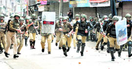 Security personnel chase away protesters at Maisuma in Srinagar on Friday