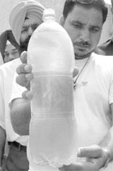 Village residents show a bottle containing impure drinking water in Mohali.