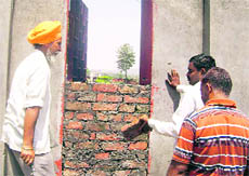 Workers of the IPH Department raise a wall to close the alleged unauthorised passage of the residence of Kangra MP Rajan Sushant at Dehri.