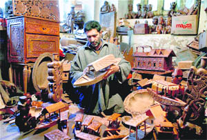 A craftsman gives the finishing touches to a model of shikara made of walnut wood at a shop in Srinagar on Sunday. 