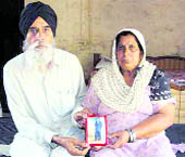 Baldev Singh and Surinder Kaur, parents of Kulwinder Singh, one of the 17 Punjabi youths on a death row in Sharjah, hold his picture at their residence