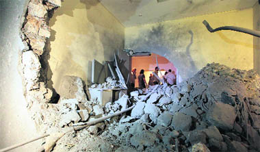 Libyan government officials inspect the damage to Gaddafis house after an air raid in Tripoli on Saturday. 