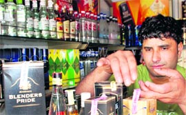 A vendor pastes stickers of purity guaranteed on liquor bottles at a vend in Raipur Kalan village in Chandigarh.