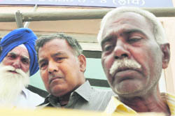 Gurdev Singh (in turban), father of Yadwinder Singh, and Parkash Chand (extreme right), father of Akshay Kumar, grieve outside a police station in Ludhiana.