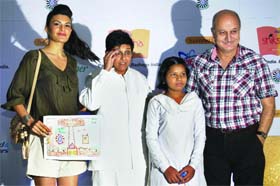 Madhu, a child of Siksha-RTI School, whose painting inspired the layout plan of the school in Purkhas, Haryana, with Bollywood actors Jacqueline Fernandes, Anupam Kher and social activist Dr Kiran Bedi in New Delhi on Wednesday