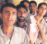 Men wait in a queue outside a polling station to cast their vote at Majalta block in Udhampur on Wednesday. T