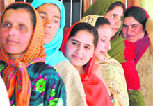 Women wait in a queue outside a polling station to cast their vote at Budagund Mawer in Kupwara district on Wednesday.