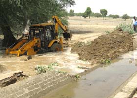 A JCB machine struggles to plug the breach near Kanwarpura village in Sriganganagar