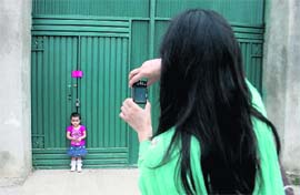 A Pakistani woman photographs her daughter against a gate of the compound where Osama bin Laden was killed, in Abbottabad 