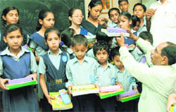 A member of the Lions Welfare Society distributes stationery items to underprivileged children at Government Model Senior Secondary School, Sector 33, Chandigarh, on Friday