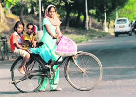MOTHERS DAY NOT FOR THEM: A mother, along with her two kids, on a bicycle on the road separating Sectors 15 and 24
