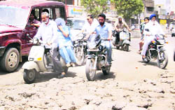 Commuters try to avoid debirs thrown by MC staff to fill potholes near the Rani Jhansi Chowk in Jagraon.