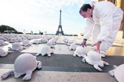 A volunteer installs 1,000 casts of German, Russian and US military helmets modelled as crawling turtles, which go on display at Trocadero, near the Eiffel Tower in Paris