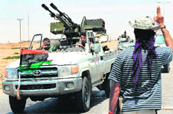 A Libyan rebel fighter welcomes comrades heading towards the front line outside Ajdabiya, where fighting between rebels and forces loyal to Gaddafi is ongoing.