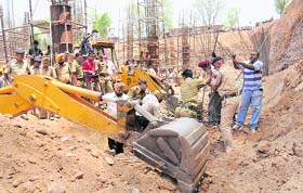 Workers of the municipal corporation dig at the site where two labourers were buried after a wall collapsed at Phase 1, Industrial Area, Chandigarh, on Thursday