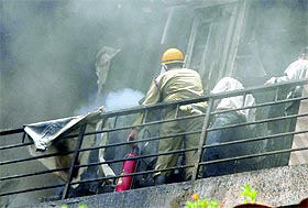 A fireman douses the flames at Frontier Raas, a sari showroom, in the South Extension area in New Delhi on Thursday.