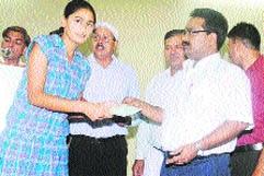 Deputy commissioner Pankaj Aggarwal gives away a cheque to a girl at a prize-distribution function in Sonepat.