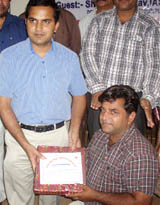 DC KK Yadav honouring Raju Chhabra on behalf of the District Red Cross Society.