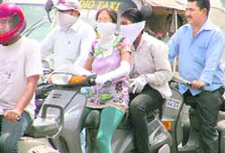 Scooterists cover their faces to escape the sun